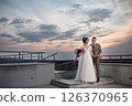 Young beautiful couple of newlywed posing in the evening against the background of an atmospheric panorama and stunning sunset 126370965