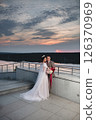 Young beautiful couple of newlywed posing in the evening against the background of an atmospheric panorama and stunning sunset 126370969