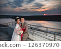 Young beautiful couple of newlywed posing in the evening against the background of an atmospheric panorama and stunning sunset 126370970