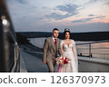 Young beautiful couple of newlywed posing in the evening against the background of an atmospheric panorama and stunning sunset 126370973
