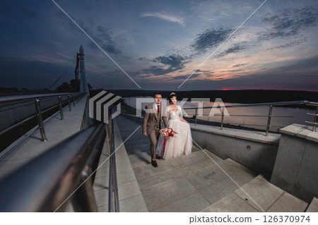 Young beautiful couple of newlywed posing in the evening against the background of an atmospheric panorama and stunning sunset 126370974