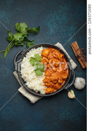 Indian dish chicken tikka masala served with rice and spices on dark blue background top view 126371080