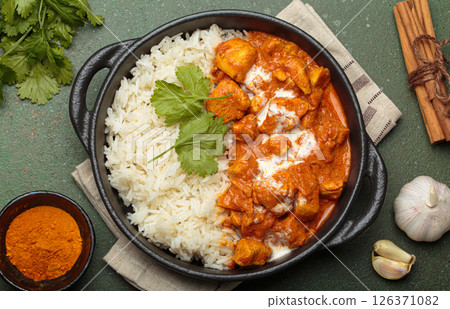 Indian dish chicken tikka masala served with rice and spices on green background top view Indian dish chicken tikka masala served with rice and spices on green background top view 126371082