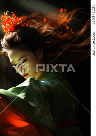 geisha woman with flower in her hair and dressed in green kimono with red flowers, dancing with red cloth on a dark background 126371220
