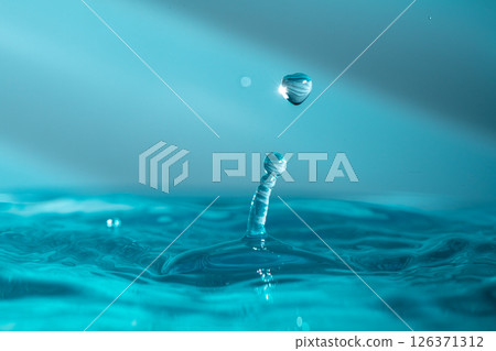 Water droplets fall down closely into the blue water, making it the perfect center in nature Water droplets fall down closely into the blue water, making it the perfect center in nature 126371312