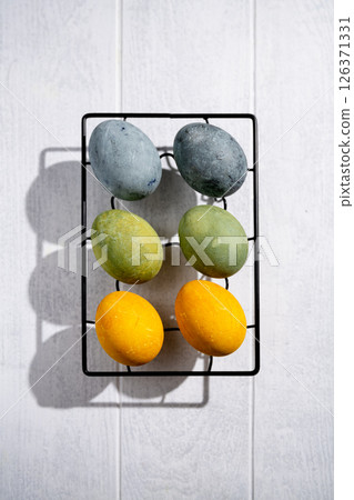 Easter eggs drying on a cooling rack after being naturally dyed with hibiscus and turmeric, creating a beautiful display of yellow and green hues, ready for easter celebration Easter eggs drying on a cooling rack after being naturally dyed with hibiscus and turmeric, creating a beautiful display of yellow and green hues, ready for easter celebration 126371331