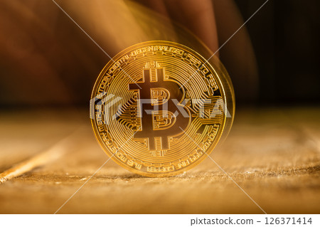 A fading, translucent, shiny gold Bitcoin rests on a textured wooden surface symbolizes the volatility of cryptocurrency, risk and uncertainty in the digital financial market. A fading, translucent, shiny gold Bitcoin rests on a textured wooden surface symbolizes the volatility of cryptocurrency, risk and uncertainty in the digital financial market. 126371414