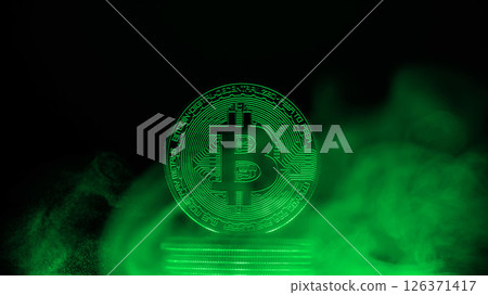 Glowing bitcoin is standing on a stack of coins surrounded by green smoke on a dark background with copy space, representing the mysterious nature of cryptocurrency 126371417