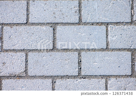 Interlocking gray concrete brick pavers forming a solid, textured pavement surface, providing versatility for various outdoor applications like walkways, patios, and driveways 126371438