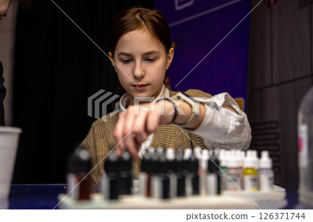 Attentive cute teen girl creating slime during master class, surrounded by ingredients and tools, diy Attentive cute teen girl creating slime during master class, surrounded by ingredients and tools, diy 126371744