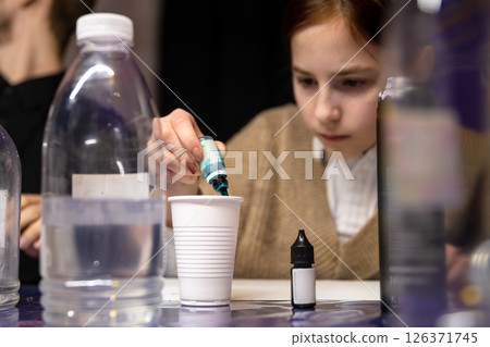 Attentive cute teen girl creating slime during master class, surrounded by ingredients and tools, diy Attentive cute teen girl creating slime during master class, surrounded by ingredients and tools, diy 126371745