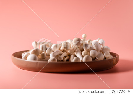 shimeji mushrooms on the plate, on pink, peach fuzz background 126372069