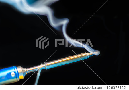 soldering iron with smoke on a black background. Electrical soldering iron with smoke on a black background. Electrical 126372122