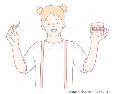 A smiling girl is holding a dental model and toothbrush to promote dental health education 126372180