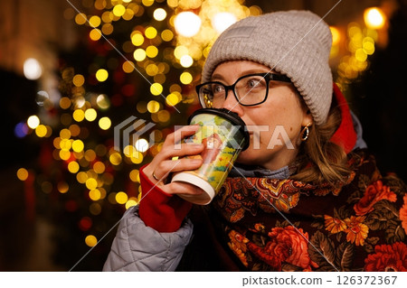Cozy winter evening with warm beverage and festive lights illuminating the joyful atmosphere 126372367