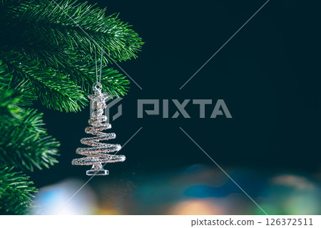 Silver glitter christmas tree ornament hanging on a christmas tree branch with bokeh lights in background with copy space 126372511