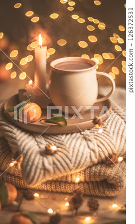 Christmas hot chocolate with tangerines and burning candles on a stack of knitted sweaters creates a cozy winter atmosphere with warm bokeh lights, Mocha Mousse Christmas hot chocolate with tangerines and burning candles on a stack of knitted sweaters creates a cozy winter atmosphere with warm bokeh lights, Mocha Mousse 126372531