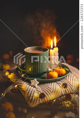 Warm cocoa, burning candles, and tangerines create a cozy atmosphere on christmas or new year's eve, surrounded by glowing lights and pine cones, greeting card Warm cocoa, burning candles, and tangerines create a cozy atmosphere on christmas or new year's eve, surrounded by glowing lights and pine cones, greeting card 126372553