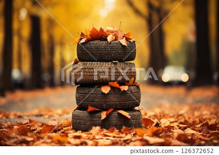 old car tires decorated with bright yellow leaves on the road in the autumn forest 126372652