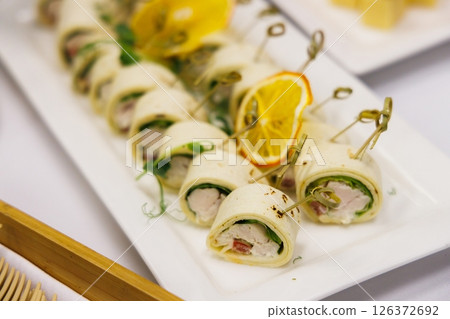 Savoring delightful chicken and vegetable rolls at a festive gathering in a cozy dining setting Savoring delightful chicken and vegetable rolls at a festive gathering in a cozy dining setting 126372692