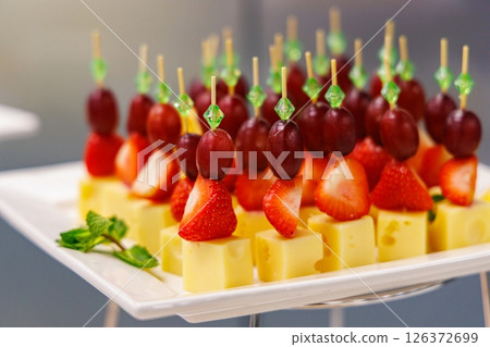 Creative fruit and cheese skewers display at a vibrant outdoor gathering in the late afternoon sunlight Creative fruit and cheese skewers display at a vibrant outdoor gathering in the late afternoon sunlight 126372699