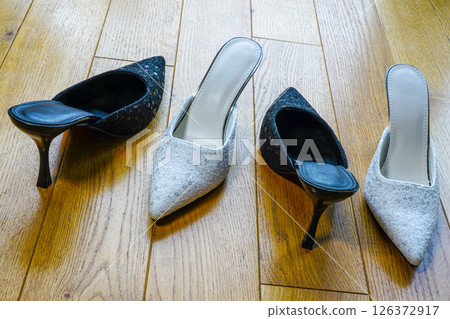 Elegant Black and Silver High Heel Mules with Sequin Details Displayed on a Wooden Floor in Daylight 126372917