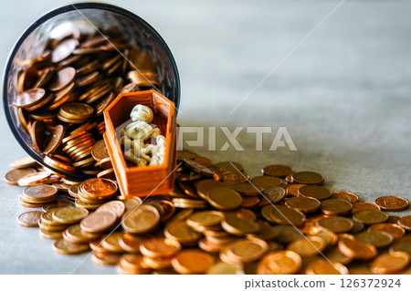 A Tiny Skeleton in a Coffin Lies Among Spilled Coins from a Jar, A Dark Symbol of Greed and Wealth 126372924