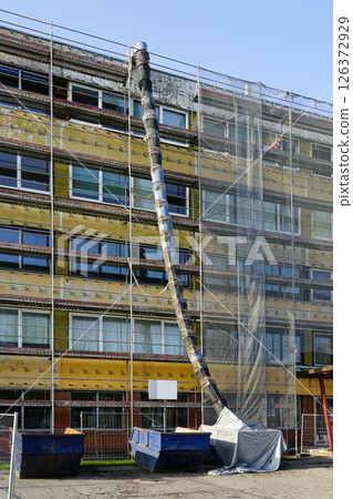 Renovation of office building covered in scaffolding and protective net during reconstruction work Renovation of office building covered in scaffolding and protective net during reconstruction work 126372929
