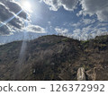 Sunlight breaking through clouds over a rugged grassy hillside 126372992