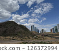 Colorful High-Rises Beside a Bare Hill Under Clouded Sky 126372994