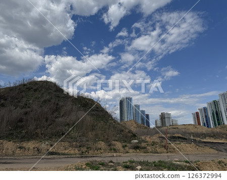 Colorful High-Rises Beside a Bare Hill Under Clouded Sky 126372994