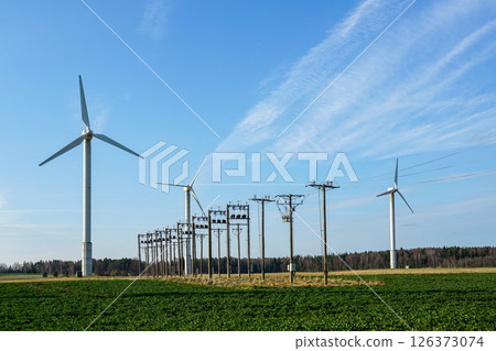 Wind Turbines and Power Lines in a Green Field Generating Clean Renewable Energy Under a Blue Sky 126373074
