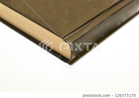 A brown book is lying on the table. 126373178