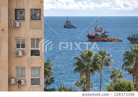 Three ships sailing on calm blue sea near residential building. Limassol, Cyprus 126373396