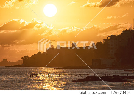 The setting sun is casting a golden glow over the city skyline of Limassol, Cyprus The setting sun is casting a golden glow over the city skyline of Limassol, Cyprus 126373404
