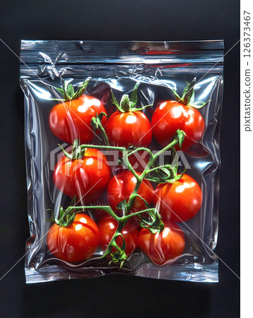 Nine ripe, red tomatoes on the vine inside a clear, airtight plastic bag, showcasing their vibrant color and freshness, with condensation visible on the inner surface of the bag Nine ripe, red tomatoes on the vine inside a clear, airtight plastic bag, showcasing their vibrant color and freshness, with condensation visible on the inner surface of the bag 126373467