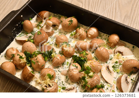 Mushrooms in cream with garlic and herbs in a baking tray, ready for baking in the oven Mushrooms in cream with garlic and herbs in a baking tray, ready for baking in the oven 126373681