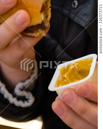 Enjoying a flavorful burger with tangy sauce during a casual meal 126373721