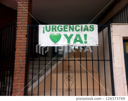 Call for immediate urgent care response sign on building gate. Advertisement "Emergency immediately" in Spanish. Urgencias ya! Call for immediate urgent care response sign on building gate. Advertisement "Emergency immediately" in Spanish. Urgencias ya! 126373789