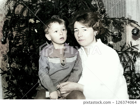 Vintage portrait of a little boy and his mother near a Christmas tree. Retro photo from 1970. Vintage portrait of a little boy and his mother near a Christmas tree. Retro photo from 1970. 126374064