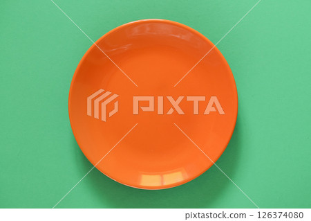 Empty Orange Ceramic Plate on Green background. Top view, copy space. Spring, Summer Menu 126374080