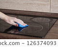 Cleaning Surface of Induction Cooker. House Cleaning Concept. Woman cleaning Glass surface of Induction cooker in Kitchen 126374093