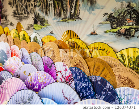 Handmade folding paper fans displayed in a colorful market stall, China 126374371