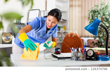 Woman in an overalls cleans table at office 126374796