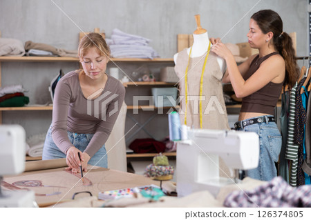 Young female dressmaker drawing on paper other work with mannequin 126374805