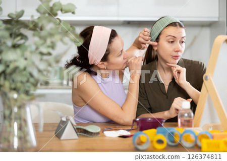 Two women looking at themselves in mirror 126374811