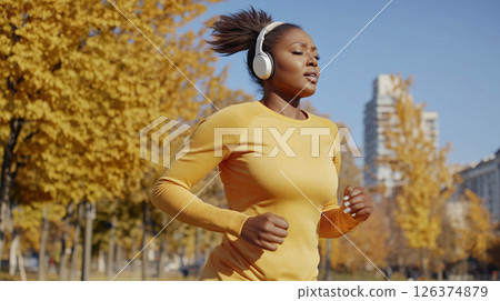 Tired African woman running outdoors in a city park on a crisp autumn morning with headphones on. Generated image 126374879
