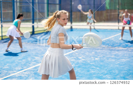 Young woman playing paddle tennis against team of women 126374932