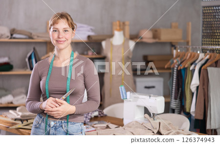 Young female dressmaker welcoming clients in sewing workshop Young female dressmaker welcoming clients in sewing workshop 126374943
