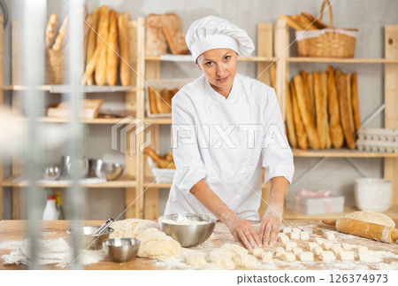 Woman works as baker in bakery, molds pies from dough, creates croissants from dough. Woman works as baker in bakery, molds pies from dough, creates croissants from dough. 126374973
